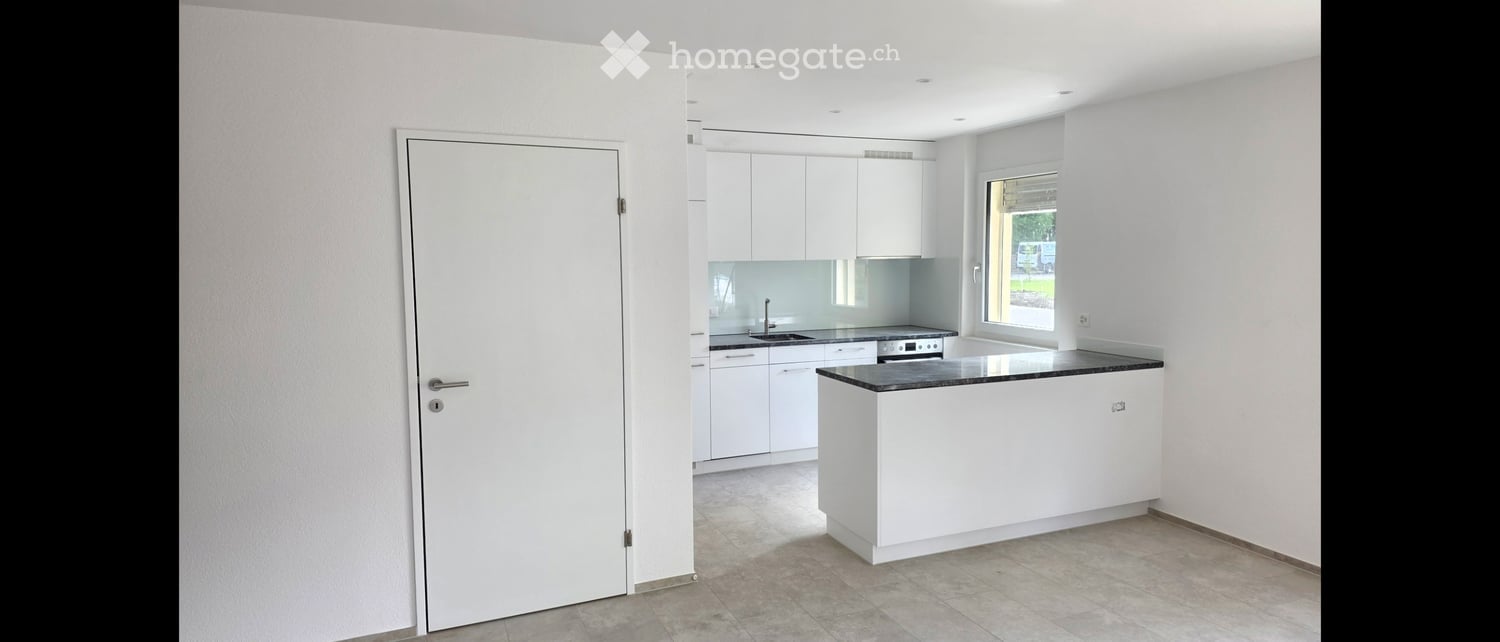 Kitchen. Modern, minimalist kitchen with white cabinets, a central island, and a black countertop.