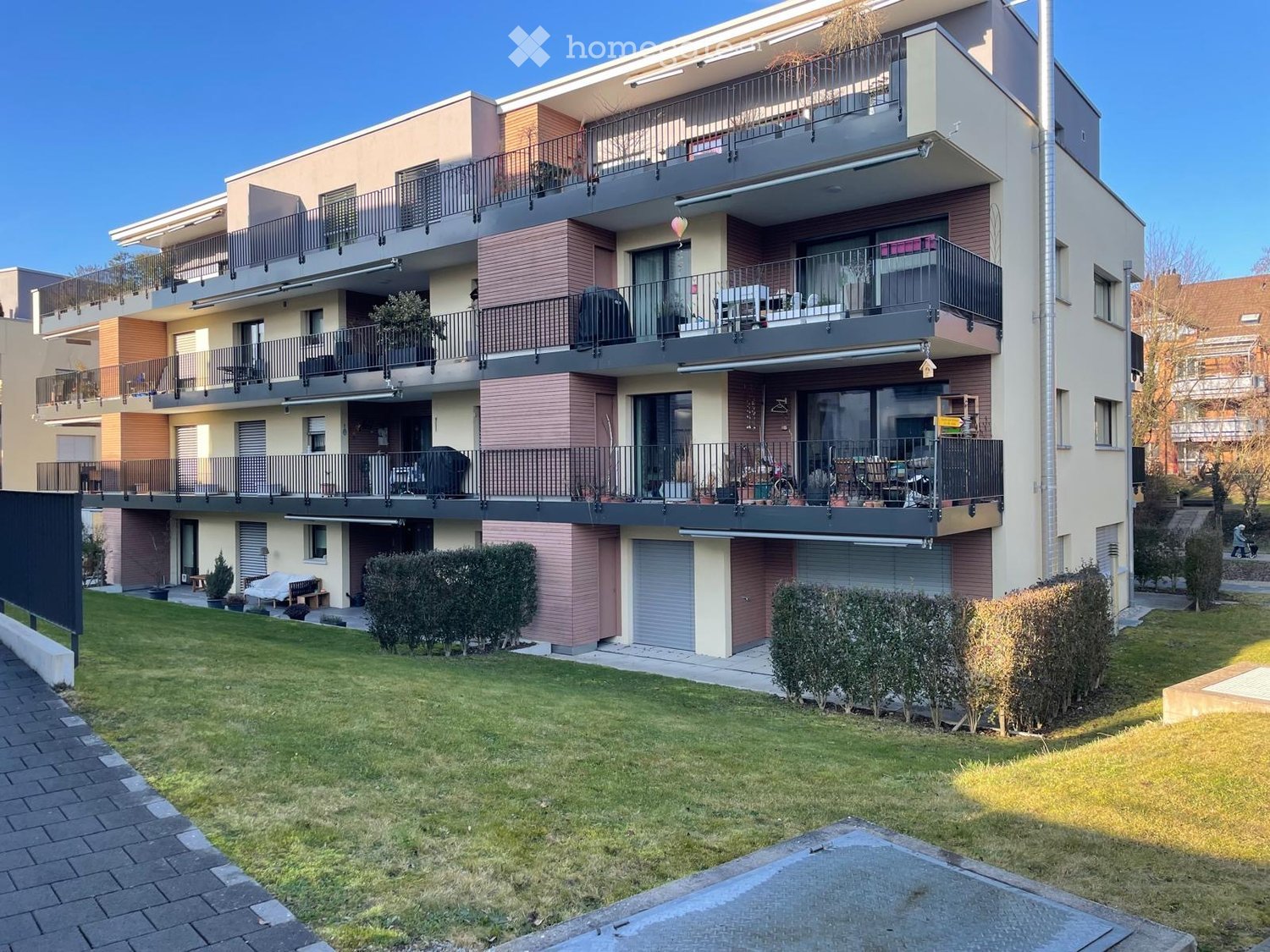 4 story apartment building, balconies, garage, lawn, shrubs