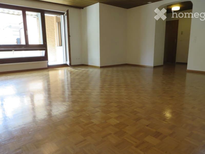 Unfurnished Room. Empty room with polished wooden flooring, large window, and open doorway leading to another space.