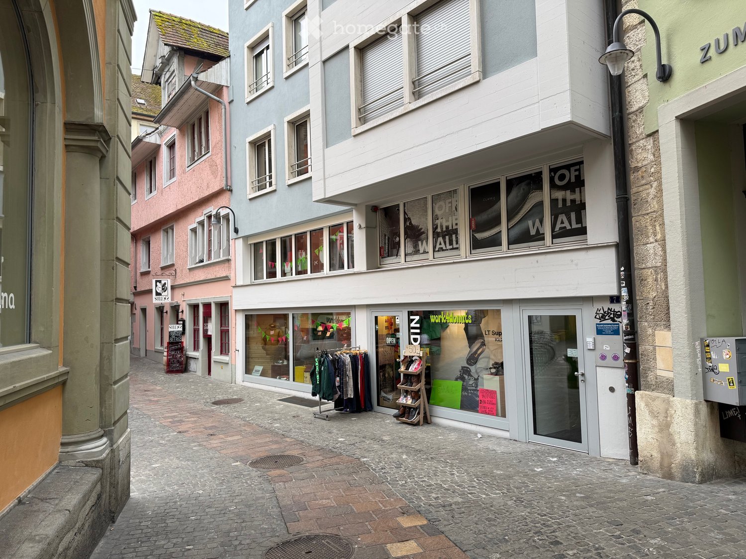 White ground floor building with many windows, entrance area, and glass door.