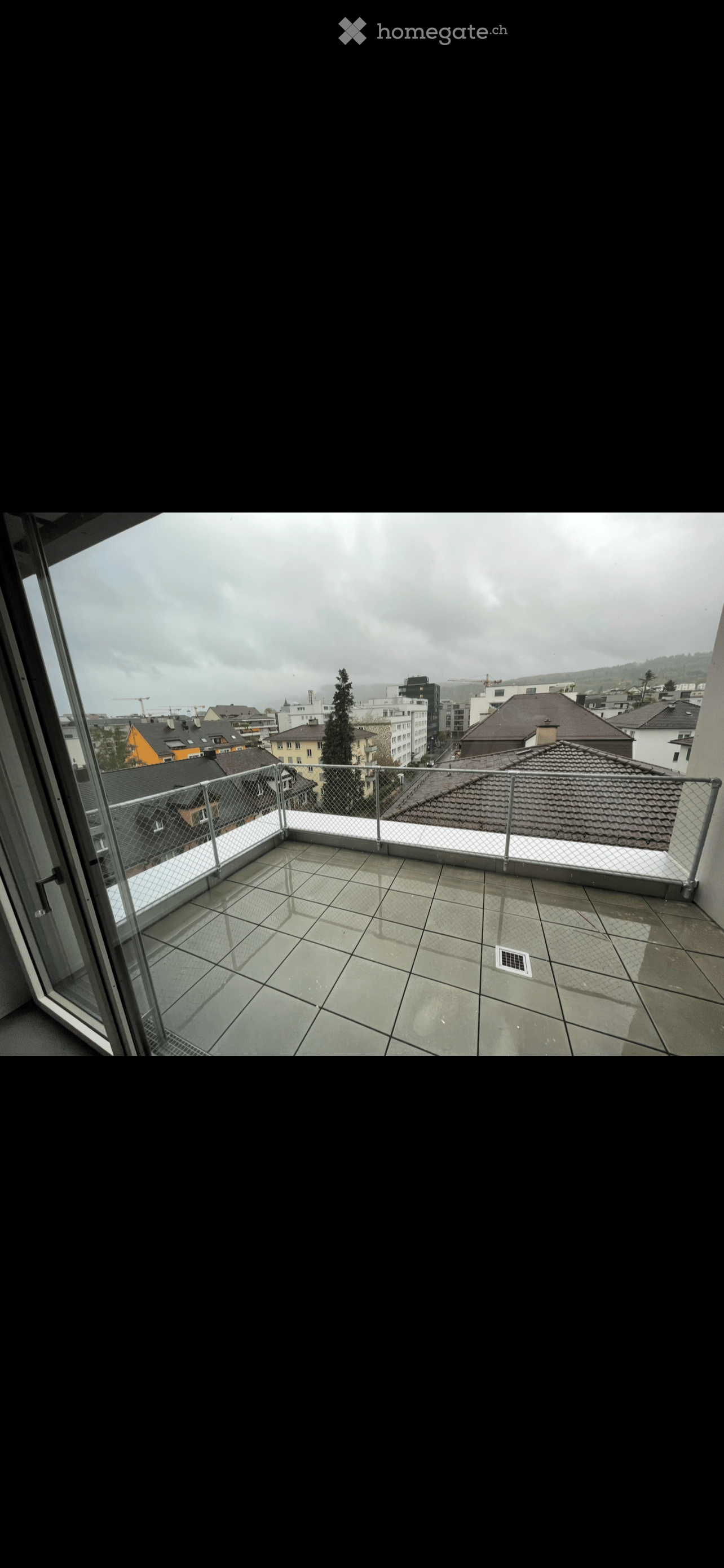 Balcony / Terrace. Balcony with tiled floor, metal railing, and a view of city rooftops and buildings under a cloudy sky.