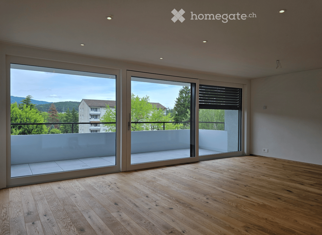 Unfurnished Room. Empty room with wooden flooring, large sliding glass doors leading to a balcony with a view of greenery and mountains.
