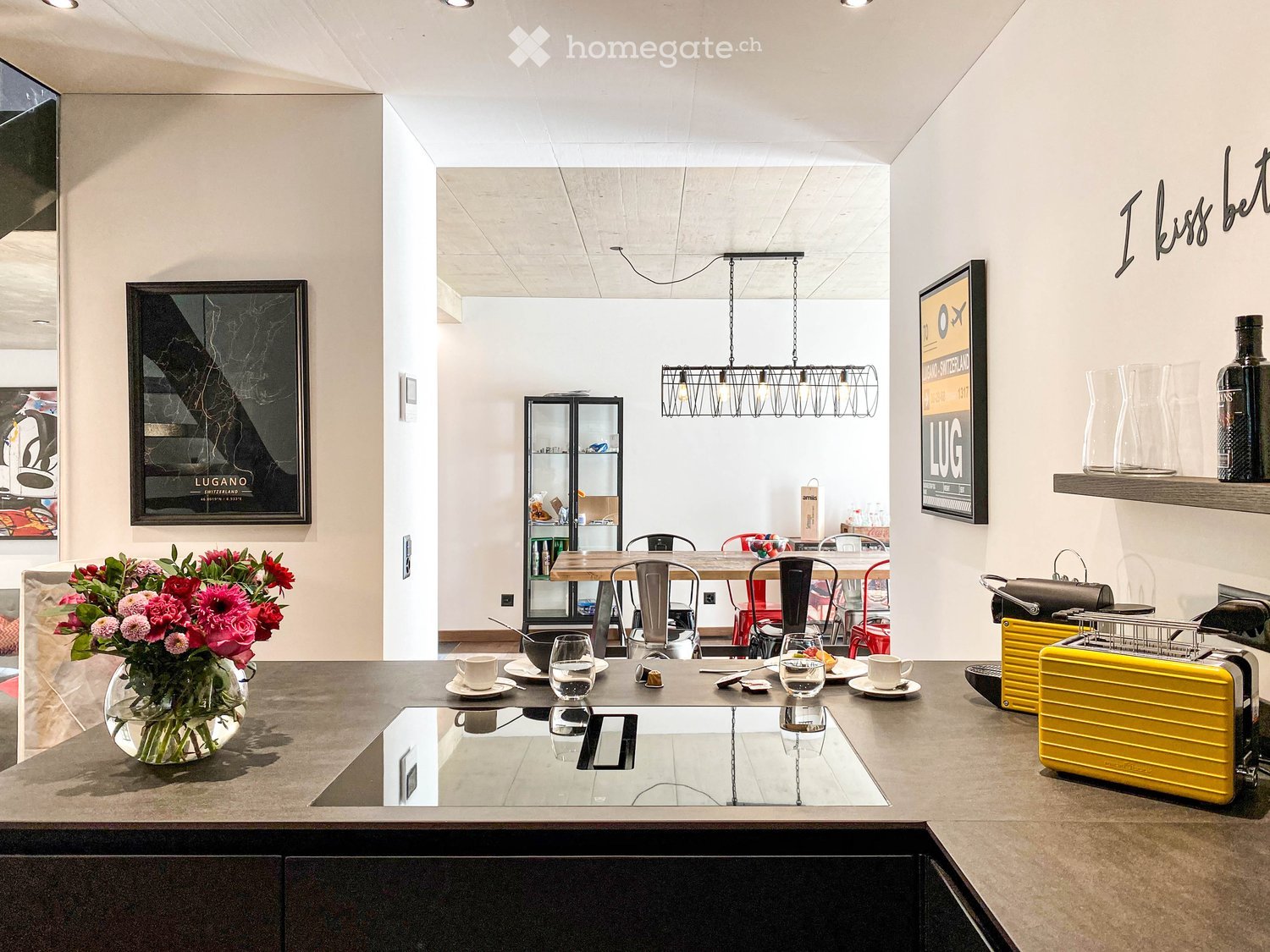 modern kitchen with island, hanging light, dining area with table, chairs and wine glasses