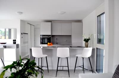 Modern kitchen with white cabinets, stainless steel appliances, island with bar stools, and a vase of flowers on the counter.