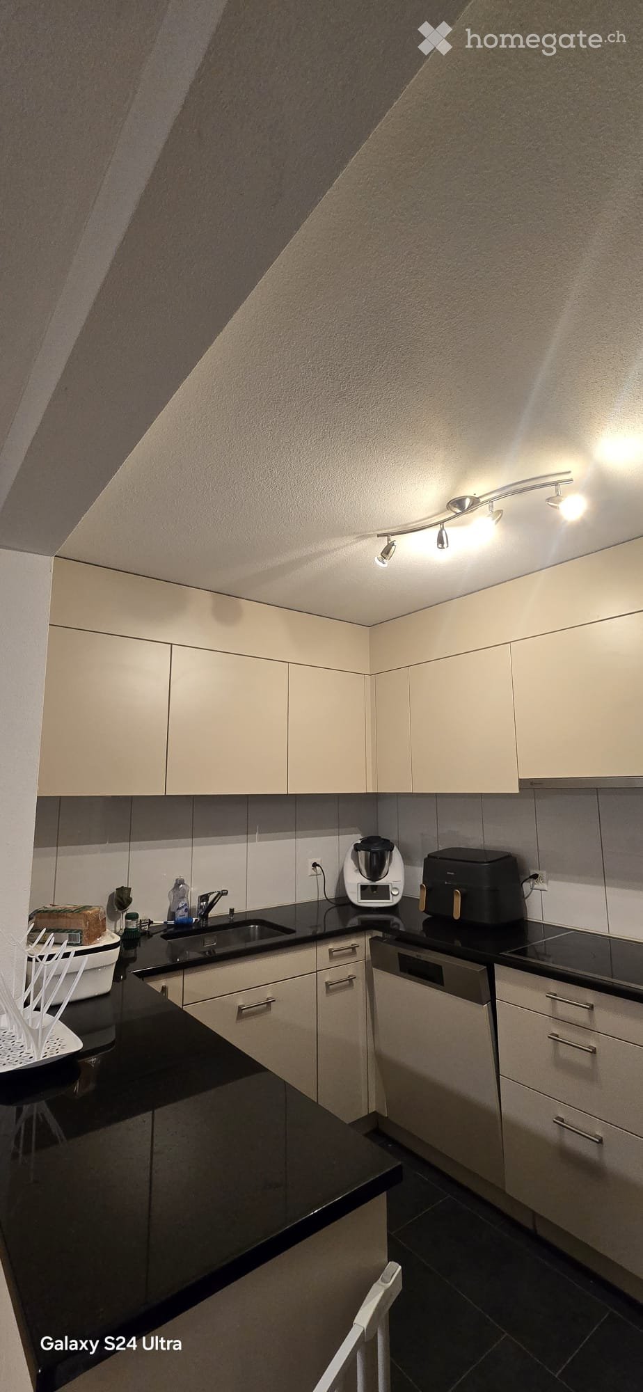 modern kitchen with black countertops, white cabinets, built-in appliances, and a dishwasher