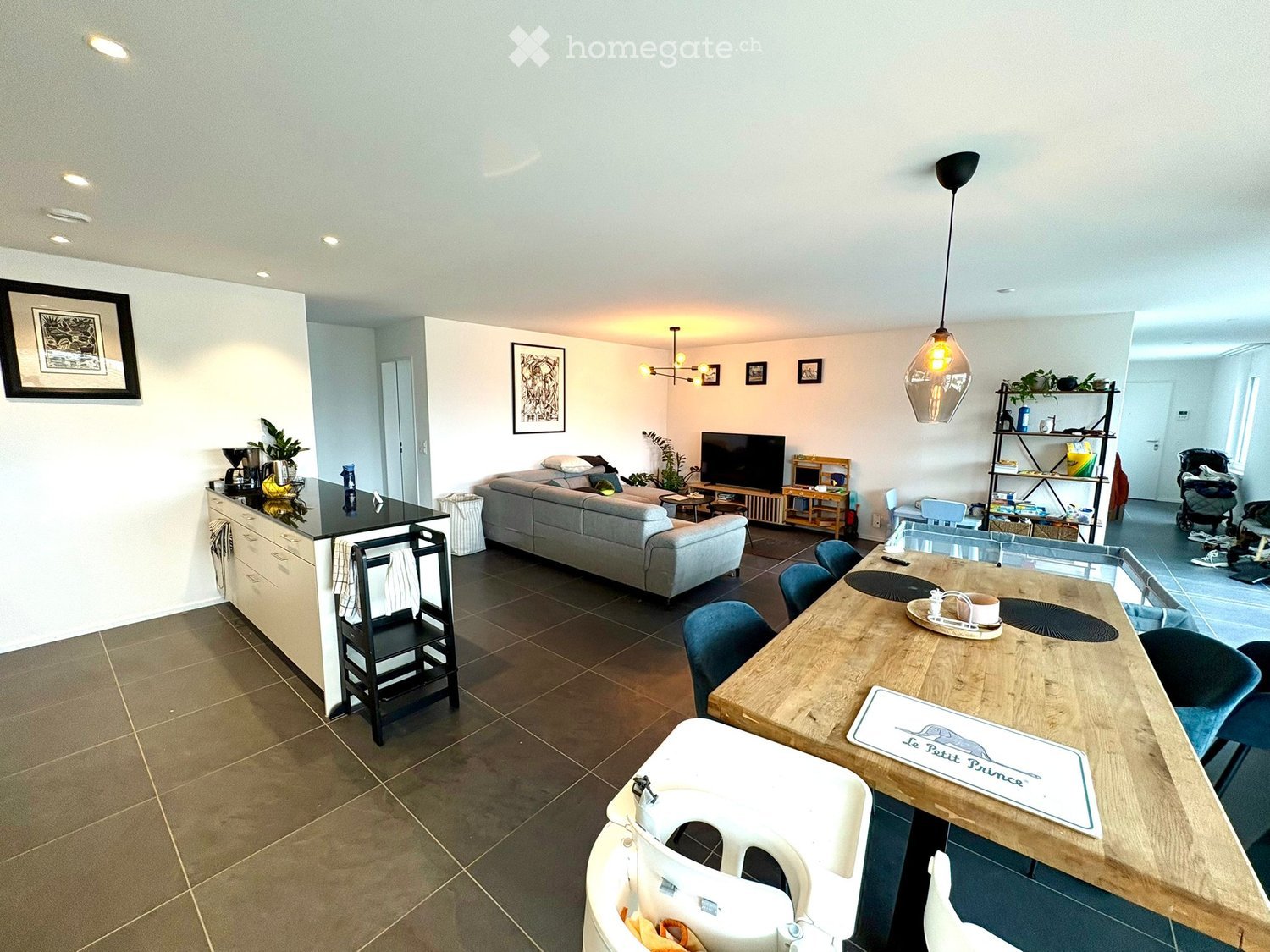 Open-plan living room and dining area with kitchen island, modern fixtures, large dining table, comfortable couch, flat-screen TV