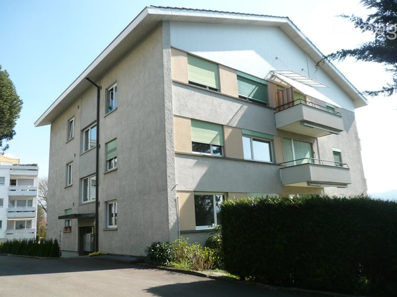 Four-story residential building with balconies, large windows, and a modern facade.