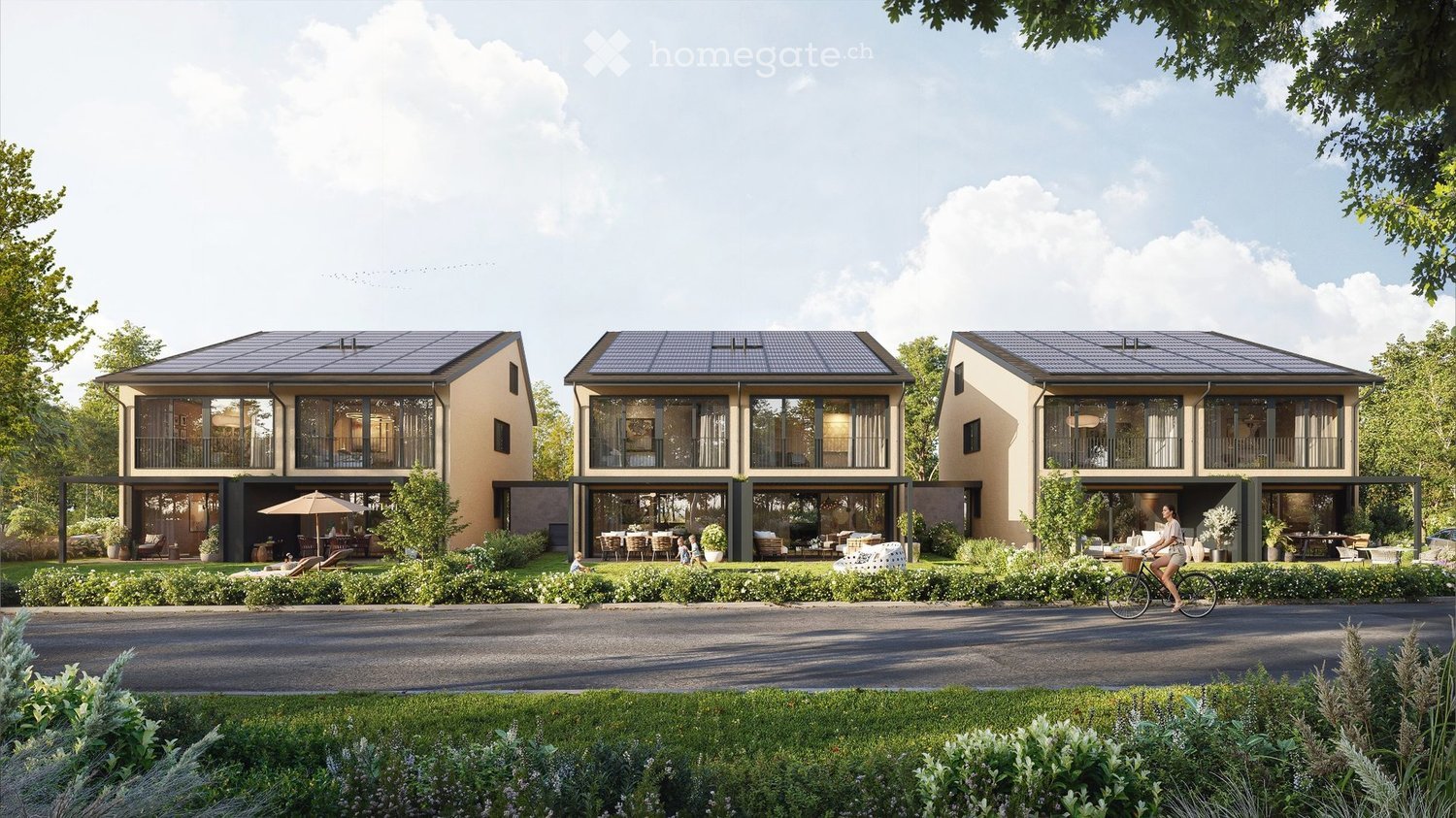 Three-story modern residential building with solar panels on the roof, large windows, and balconies. The building is surrounded by a well-maintained garden with seating areas, outdoor furniture, and a paved driveway.