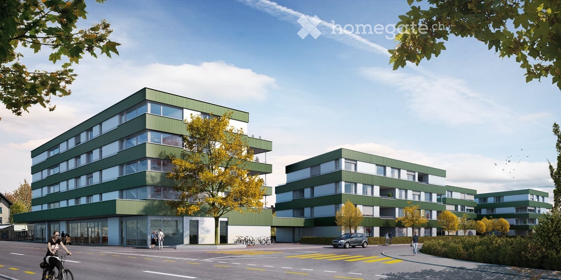 Modern multi-story residential building with green and white facade, large windows, and balconies. The building is surrounded by trees and has a parking area in front.