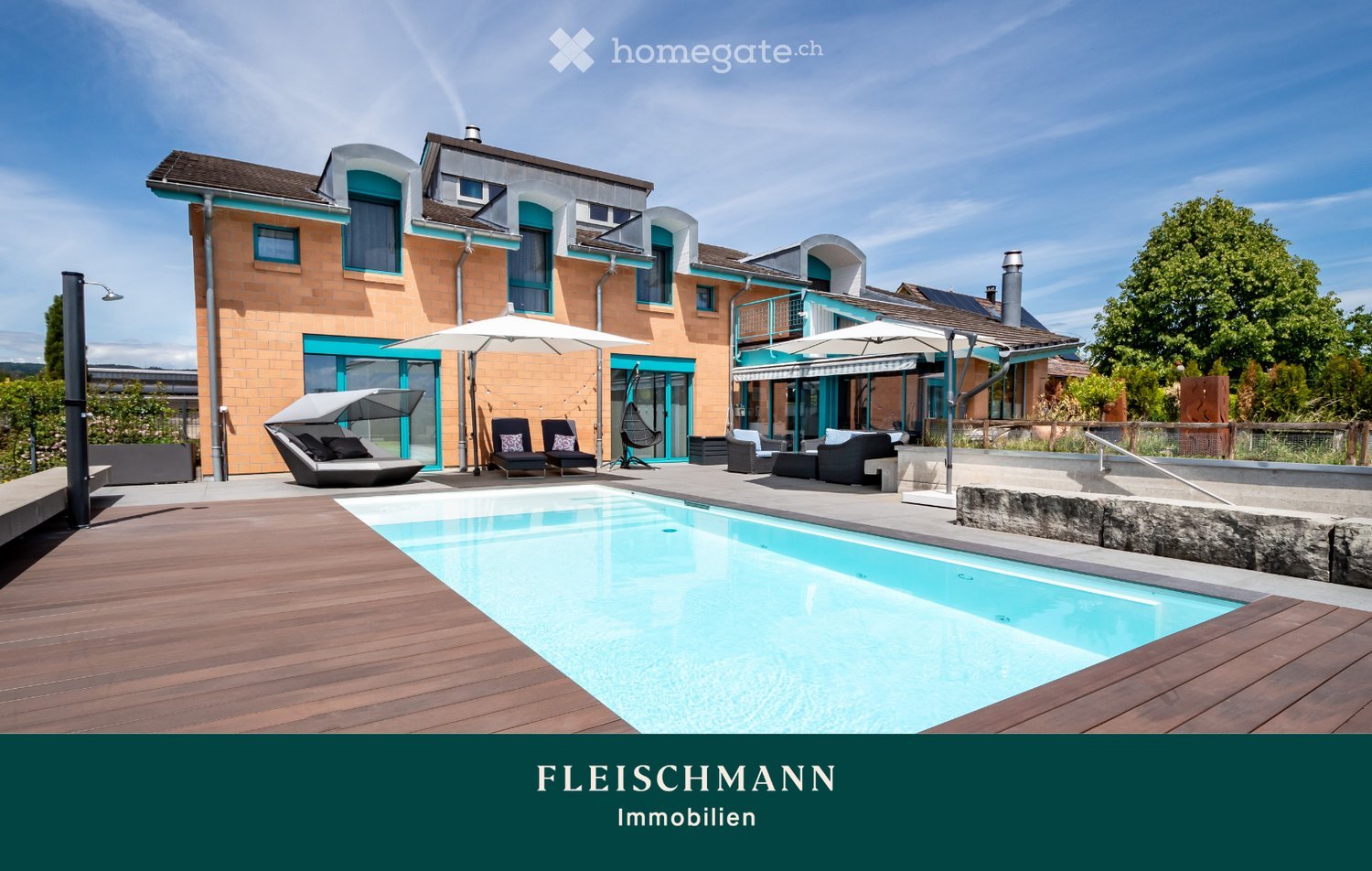 Modern house with a spacious outdoor area featuring a swimming pool, lounge chairs, umbrellas, and a wooden deck.