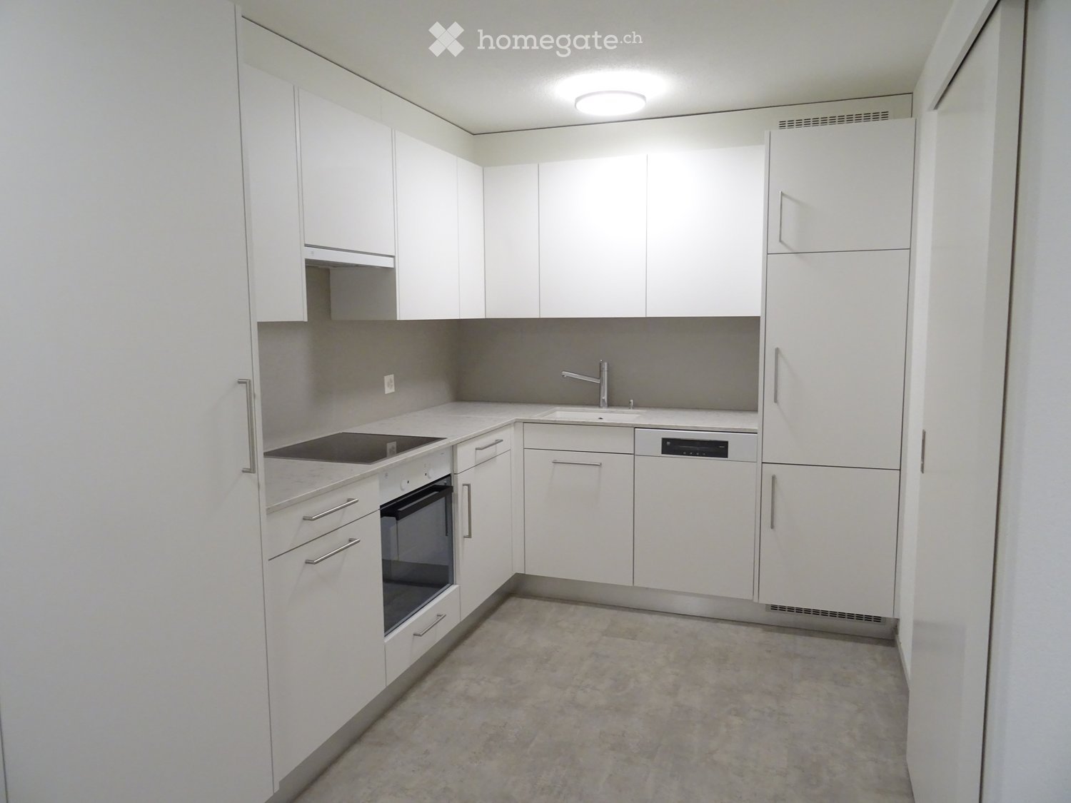 Modern kitchen with white cabinets, stainless steel appliances, and a grey backsplash.