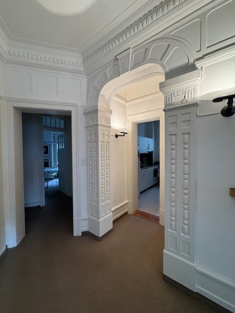 Empty hallway, white walls, decorative ceiling, floor, 2 doors leading to the kitchen and another room