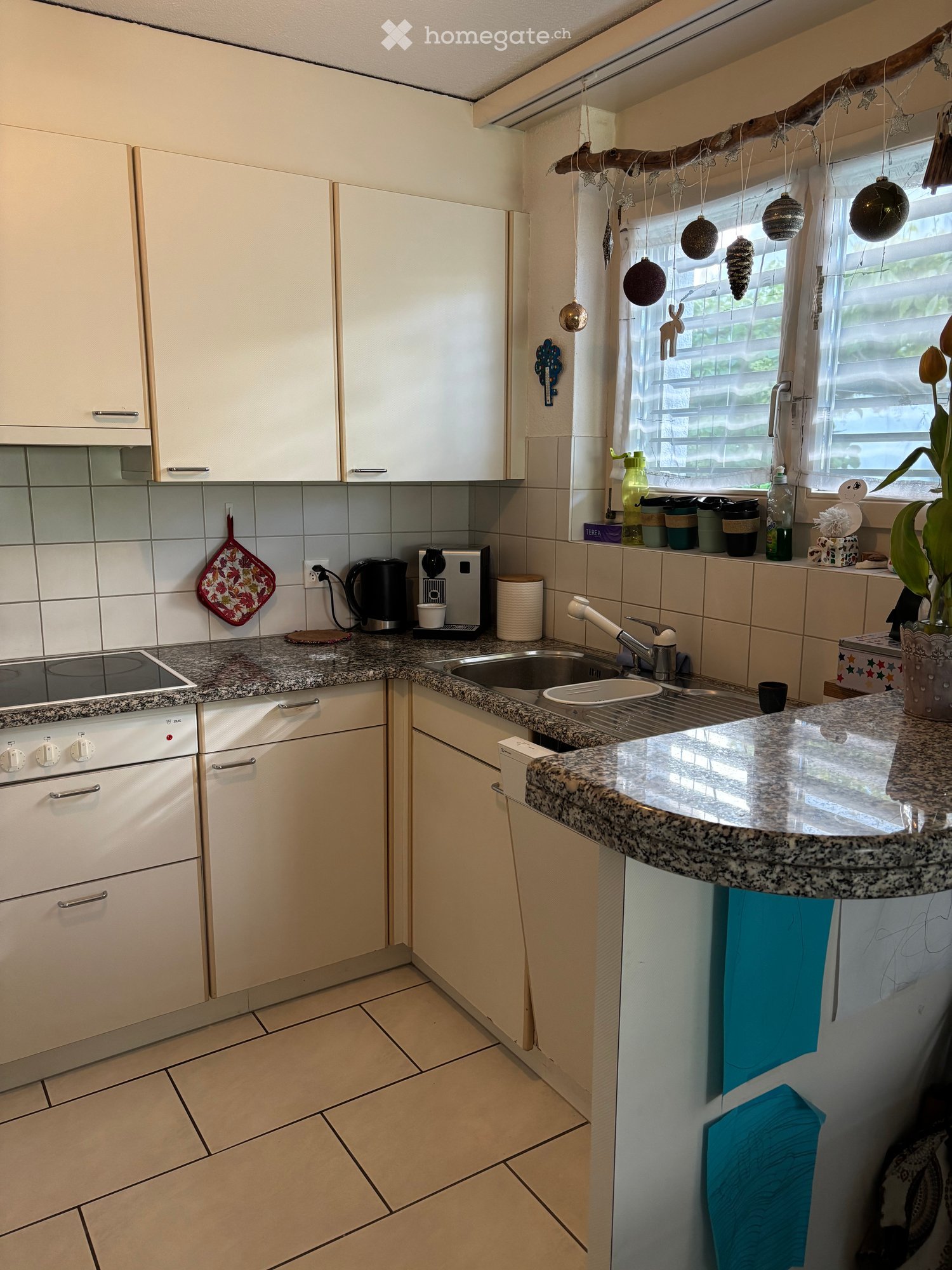 Modern kitchen with white cabinets, granite countertops, and stainless steel appliances. Features an electric stove, sink, and various kitchen items on the counter.