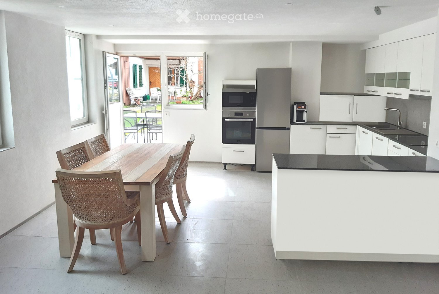 modern kitchen with dining area, wooden table, chairs, white cabinets, black countertops, stainless steel appliances, microwave, oven, refrigerator, sink, faucet, windows, sliding door, garden view