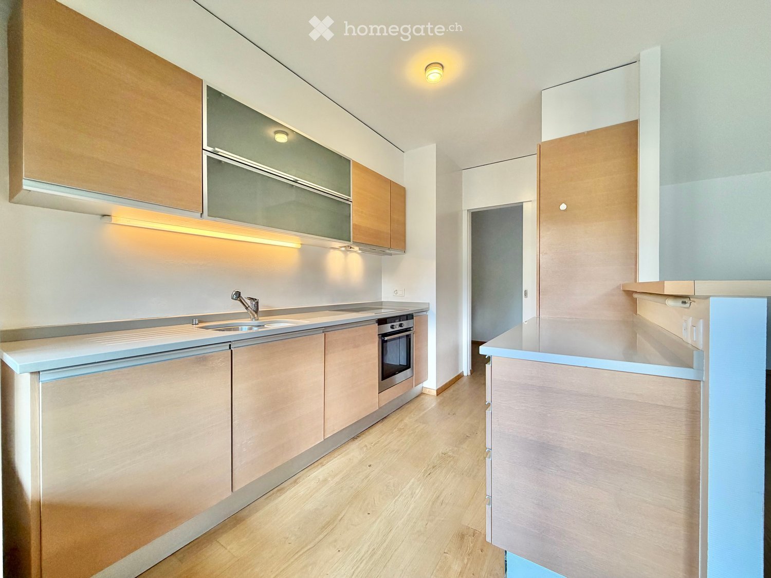 Modern kitchen with light wood cabinets, stainless steel appliances, and a central island.