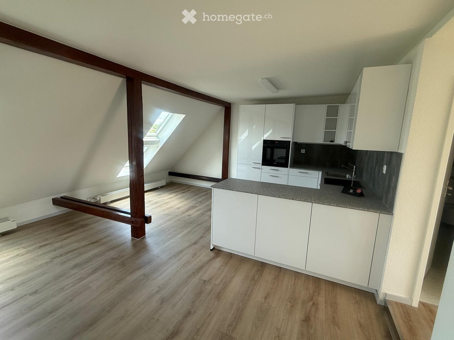 Modern kitchen with white cabinets, granite countertop, and wooden flooring. Features a skylight window and built-in appliances.