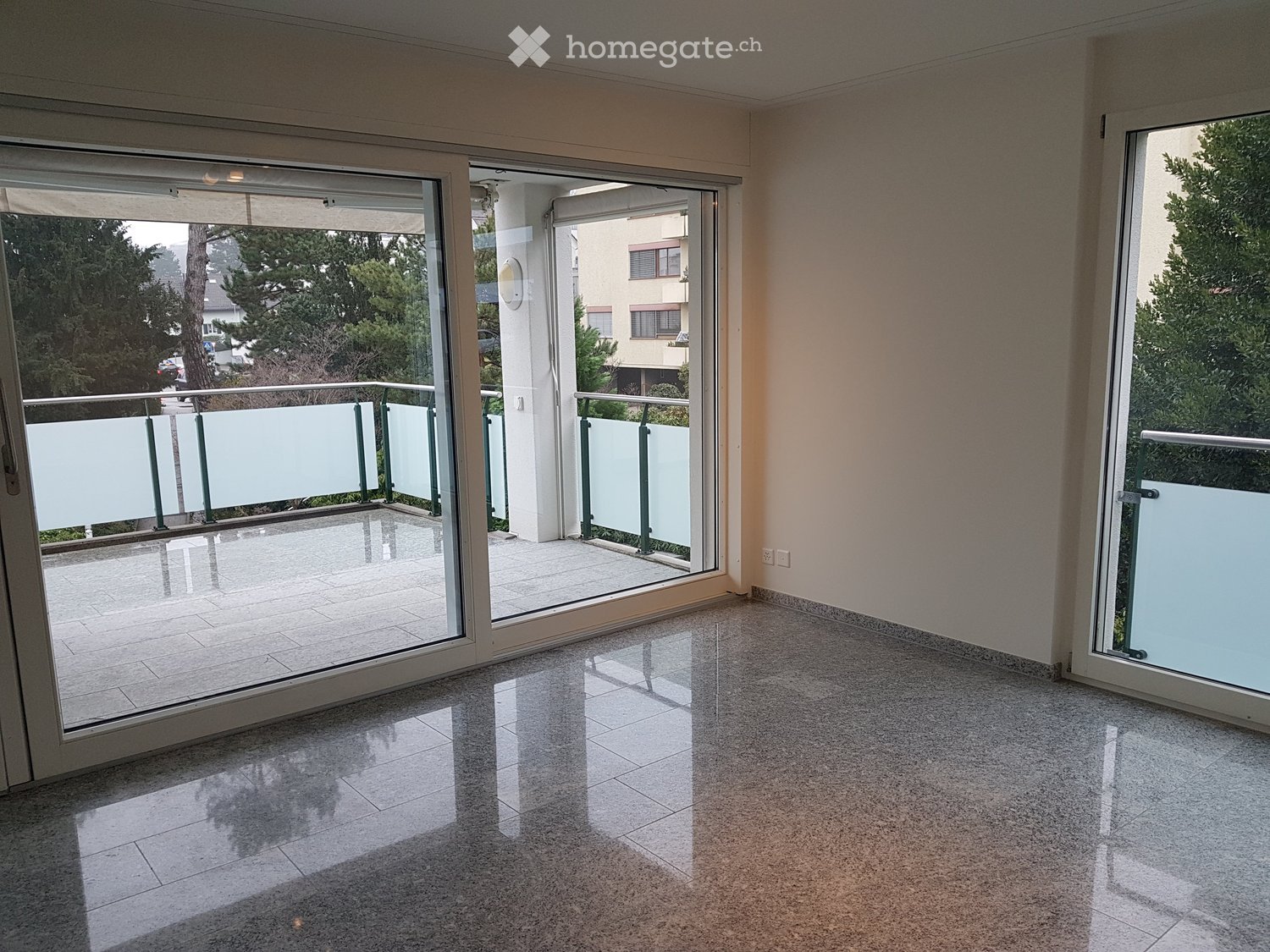 Empty room with large sliding glass doors leading to a balcony, tiled floor, and light-colored walls.