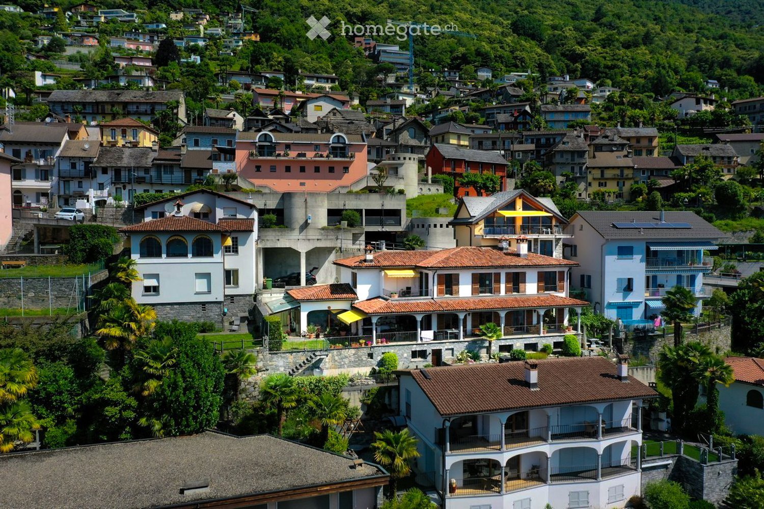 cluster of villas on a hillside, balconies, terraces, surrounding greenery, views of mountains