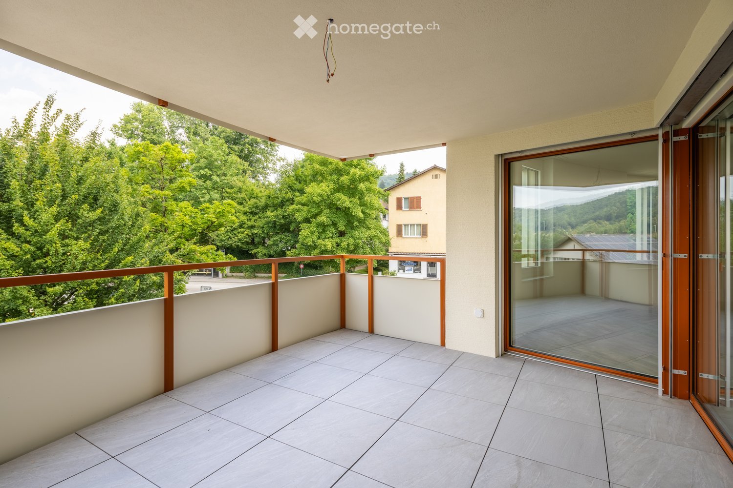Balcony / Terrace. Empty balcony with tiled floor, wooden railings, and glass doors.