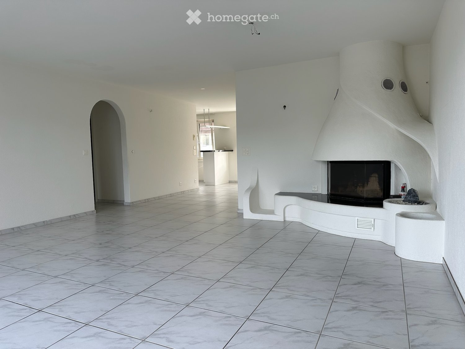 Bright, modern hallway with white walls, tiled floor, and a built-in fireplace with a decorative stone centerpiece.