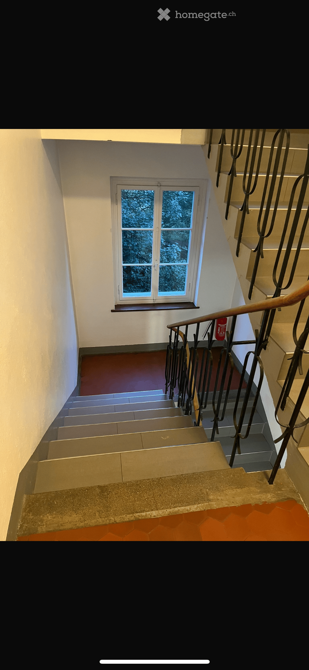 Staircase with metal railing, wooden handrail, and a window overlooking a snowy outdoor scene.