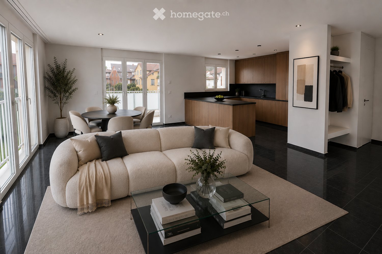 Modern living and dining area with a curved sofa, coffee table, dining table with chairs, kitchen area with cabinets and sink, and decorative items including books, vases, and a picture frame.