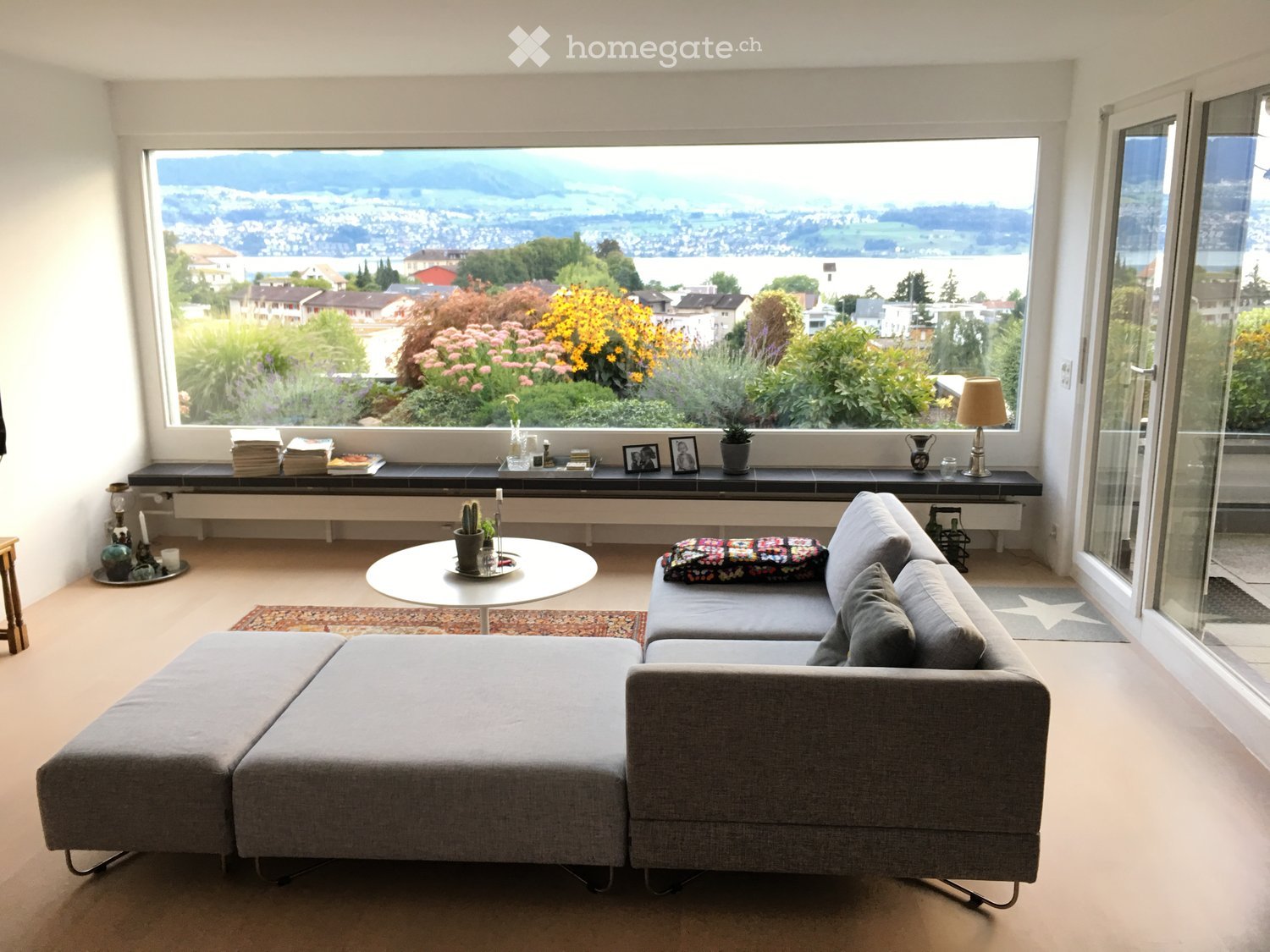 large living room with a couch, coffee table, and a large window with a view of the city