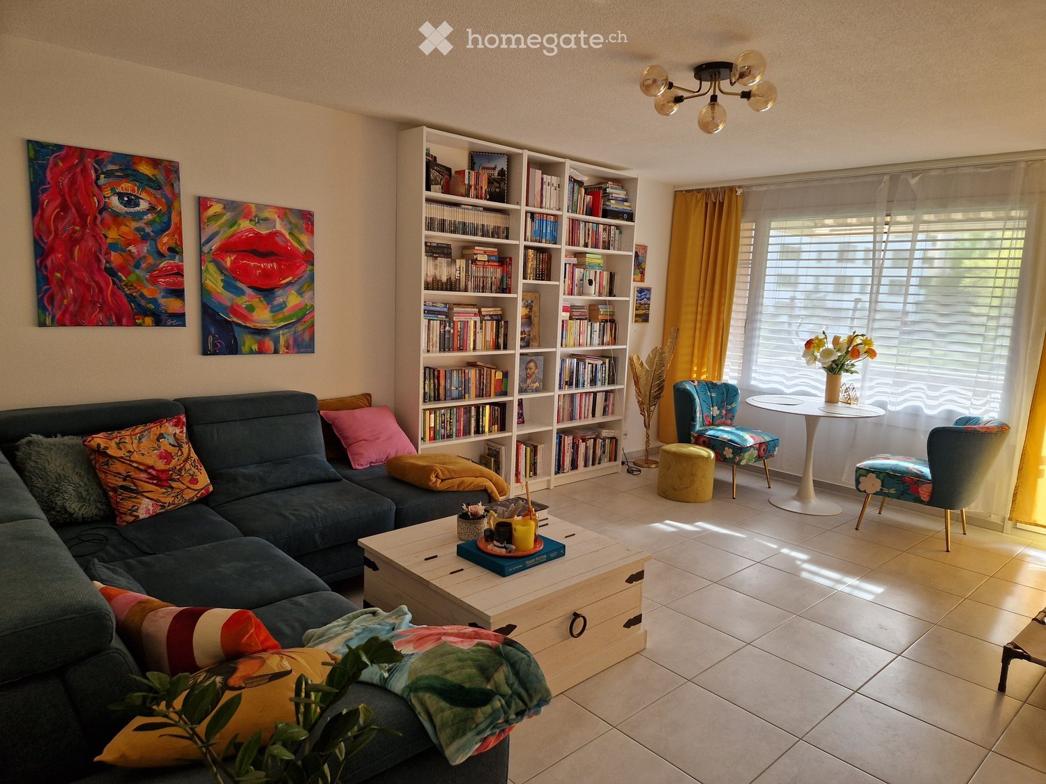 Living room with a couch, coffee table, bookshelves, and a window with a view