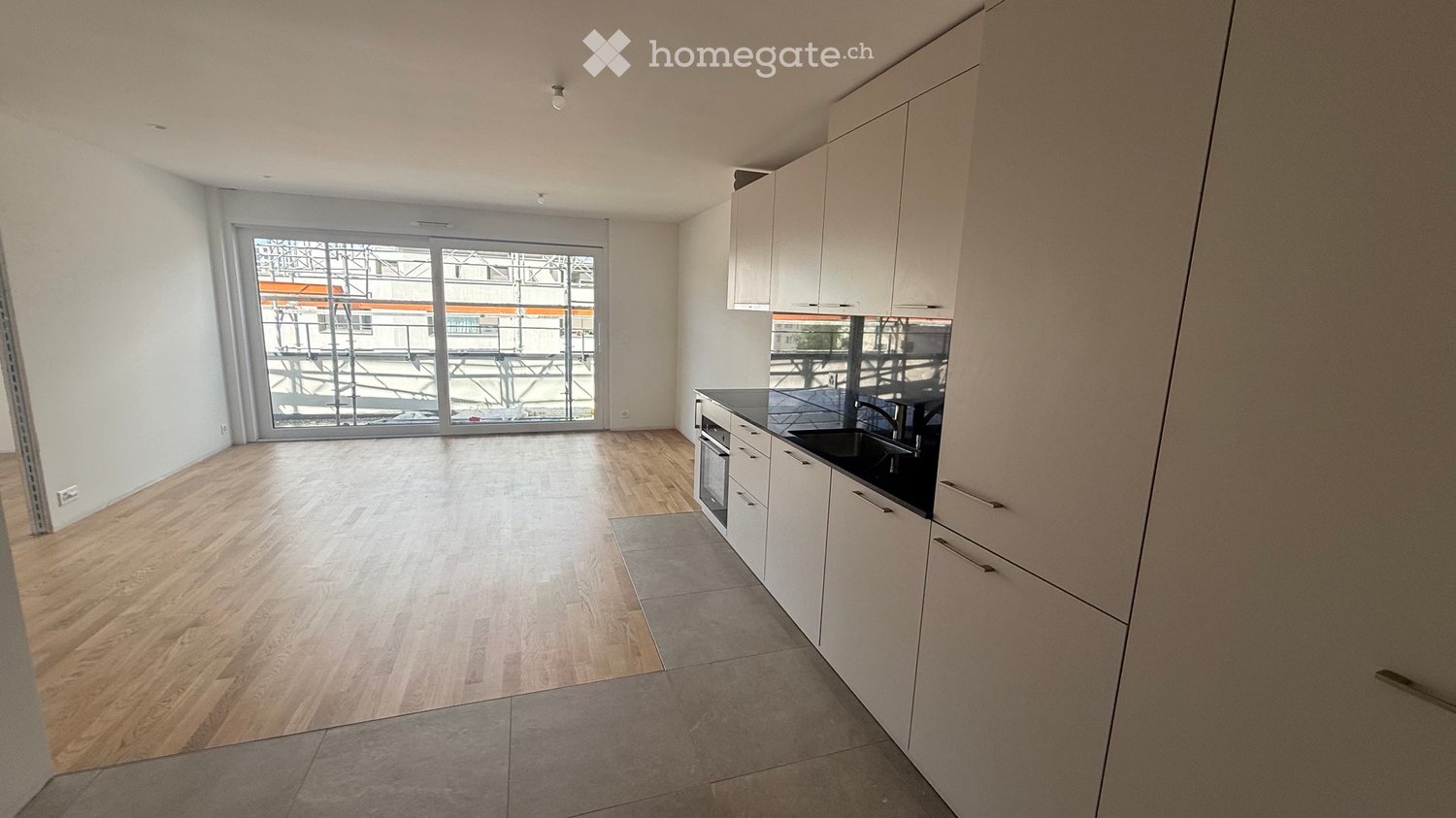 Modern kitchen with white cabinets, black countertop, and a large window overlooking an outdoor area.