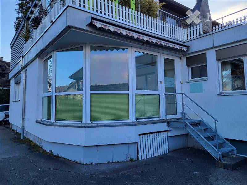 White apartment building, large arched windows, metal railing, entrance stairs, front balcony with fence