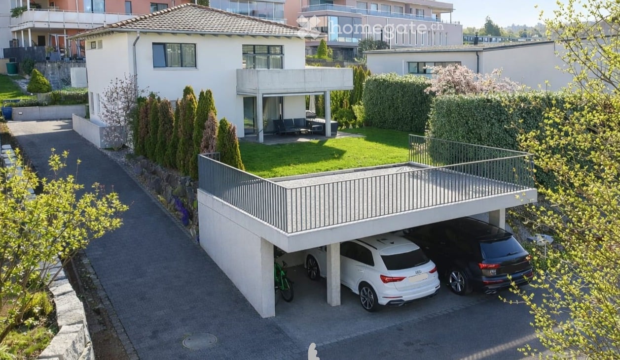 Modern two-story house with a garage, balcony, and well-maintained garden.