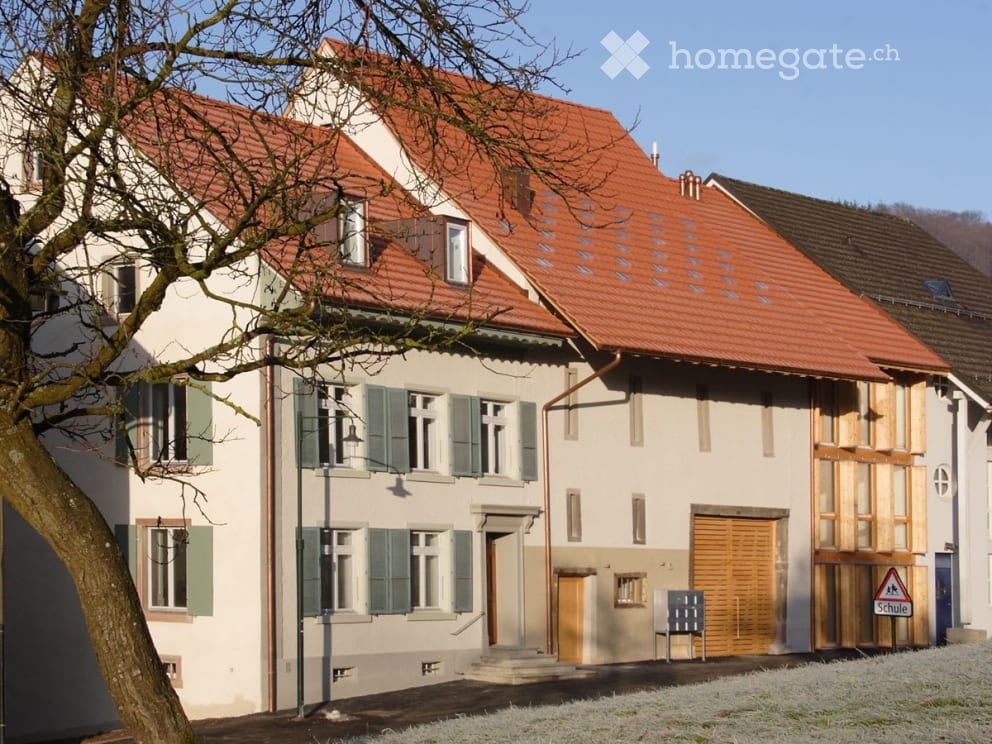 2 story building, red roof, white walls, green shutters, tree in front, garage