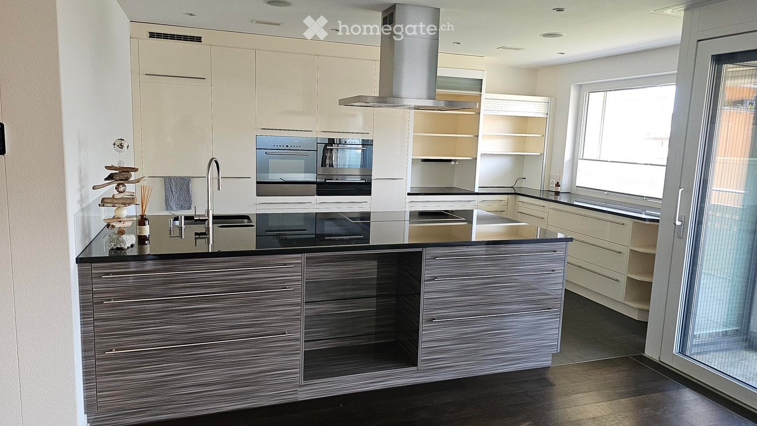 Modern kitchen with sleek, grey cabinets, stainless steel appliances, and a black countertop island.