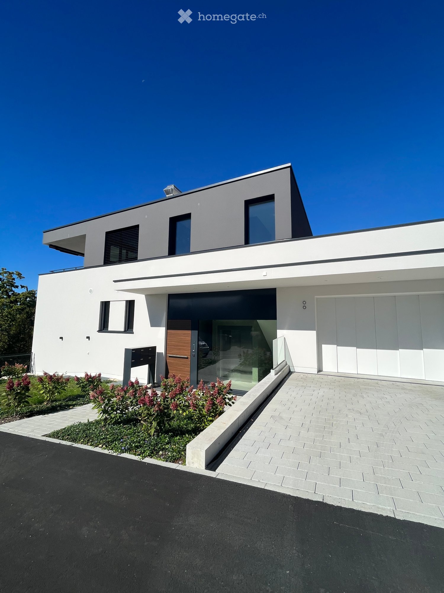 Modern 2-storey house, white exterior, grey trim, large windows, garage doors, driveway