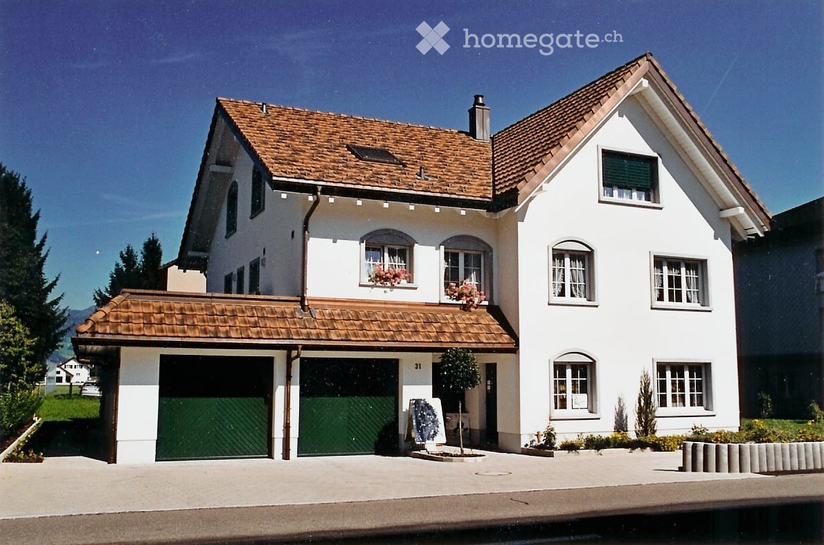 Two-story white house with brown tiled roof, garage, and flower boxes on windows.