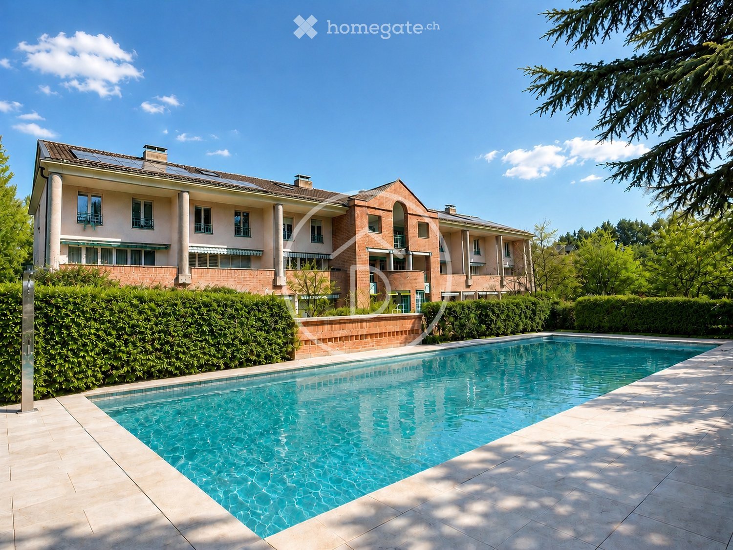 Two-story house with brick and white facade, multiple windows, and a large swimming pool in the foreground.
