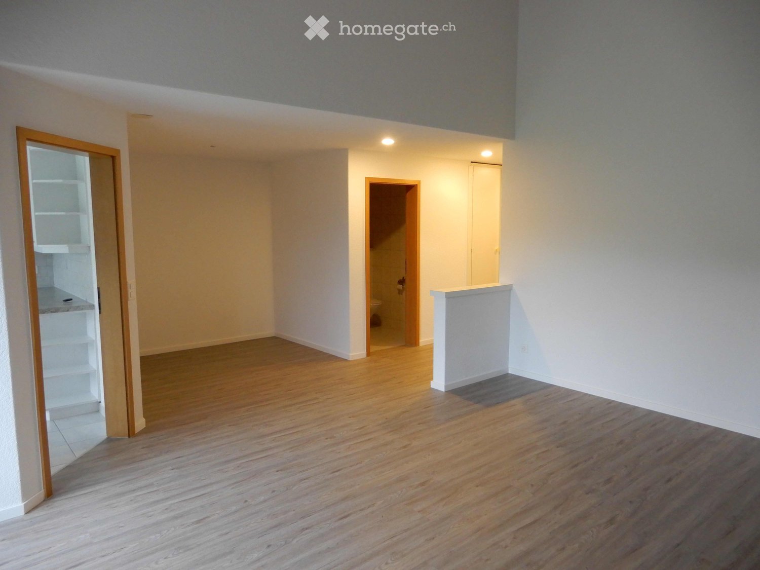Empty room with wooden flooring, white walls, and two open doorways leading to other spaces.