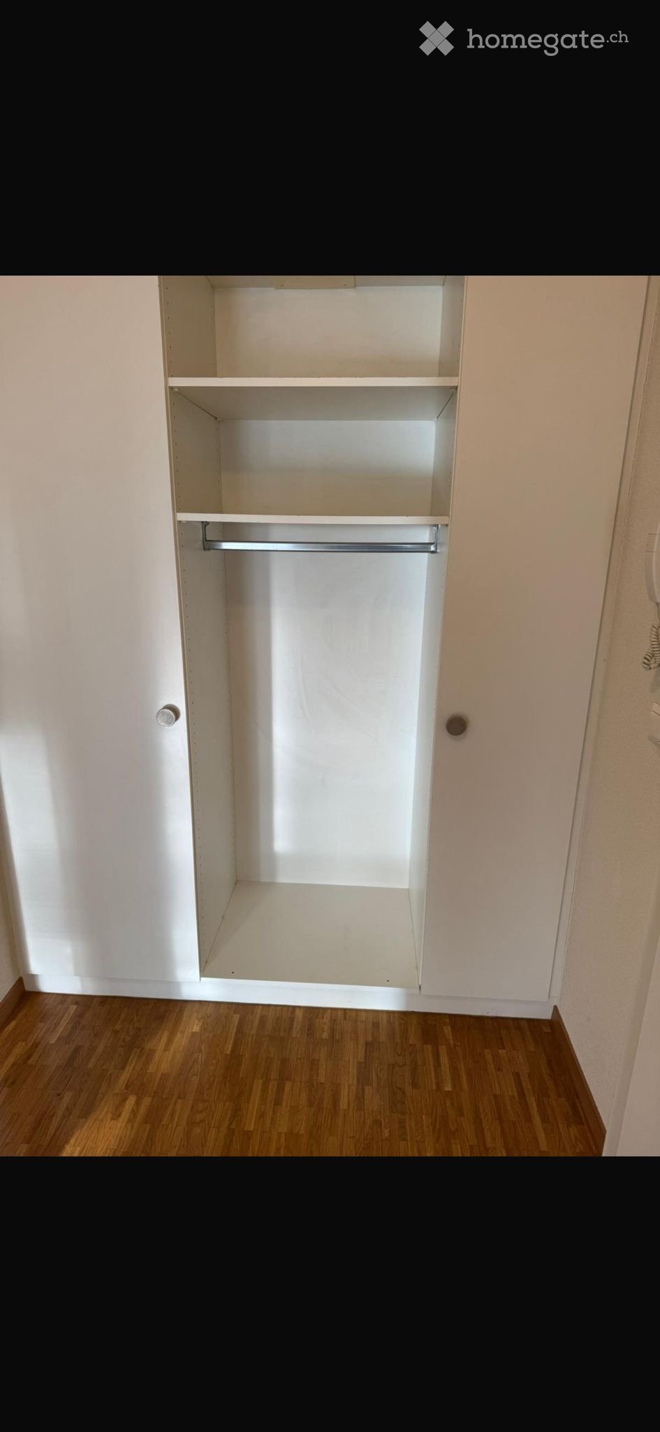 Empty room with wooden flooring and a built-in closet with shelves and a hanging rod.