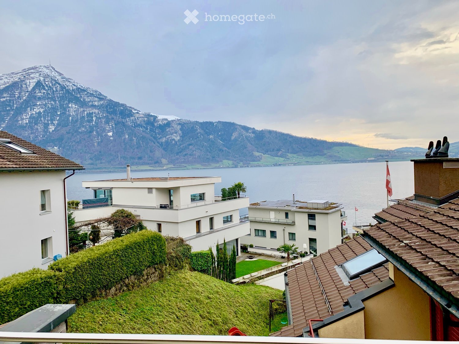 House. Modern house with lake view, brown roof, white walls, balcony, garden, flag
