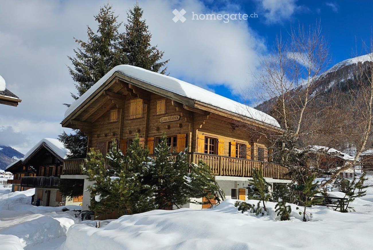 wooden chalet, snow on the roof, wooden balcony, yellow shutters, surrounded by trees and snow