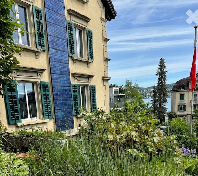 3 story house, blue solar panels, green shutters, garden, lake view