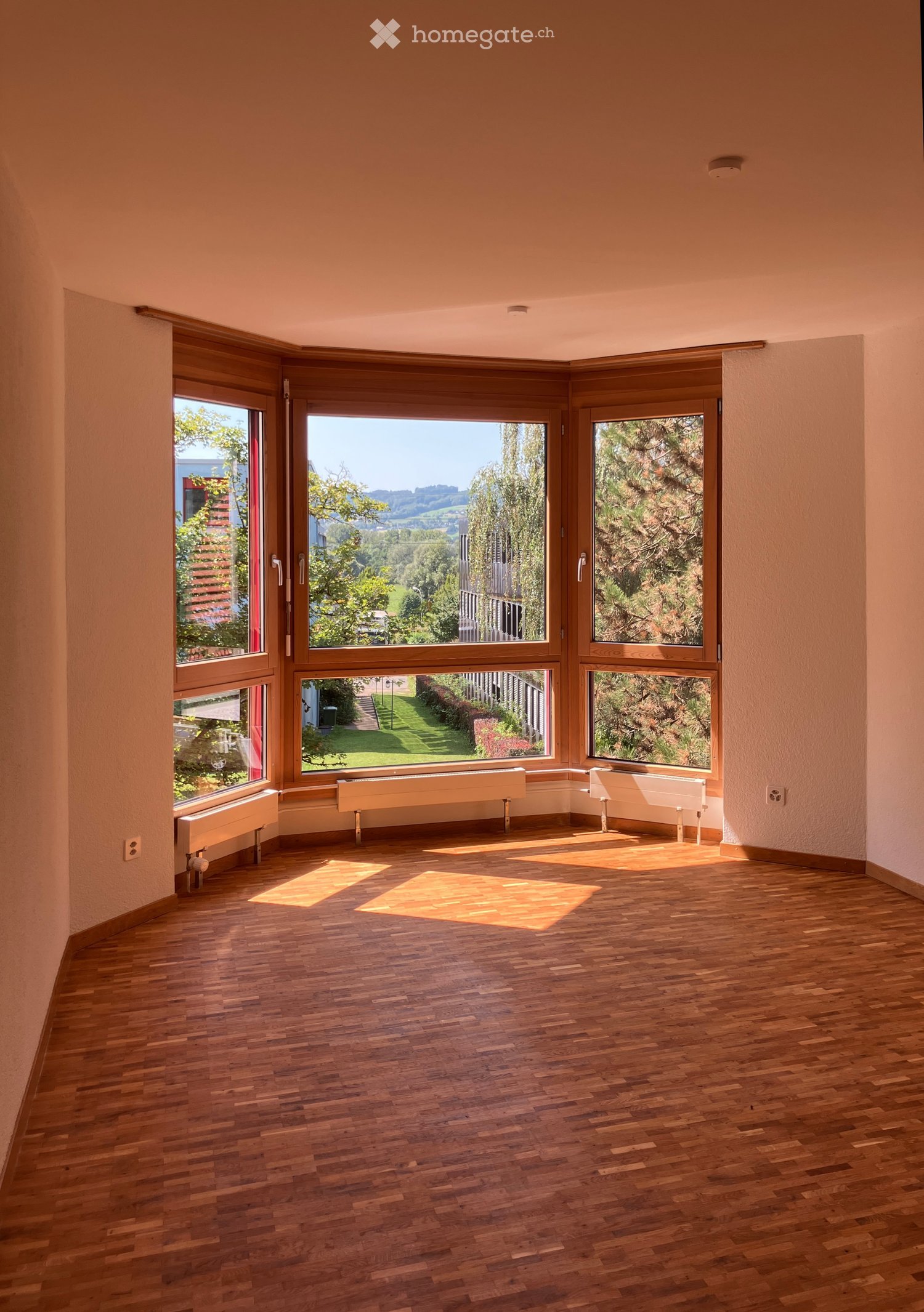 Unfurnished Room. Empty room with wooden flooring, large windows, radiators, and natural light. No furniture or equipment present.