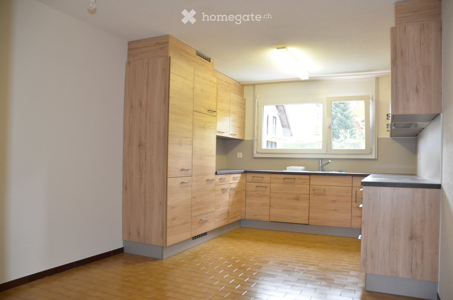 empty kitchen with wooden cabinetry, tile flooring, granite countertops, windows, sink with faucet