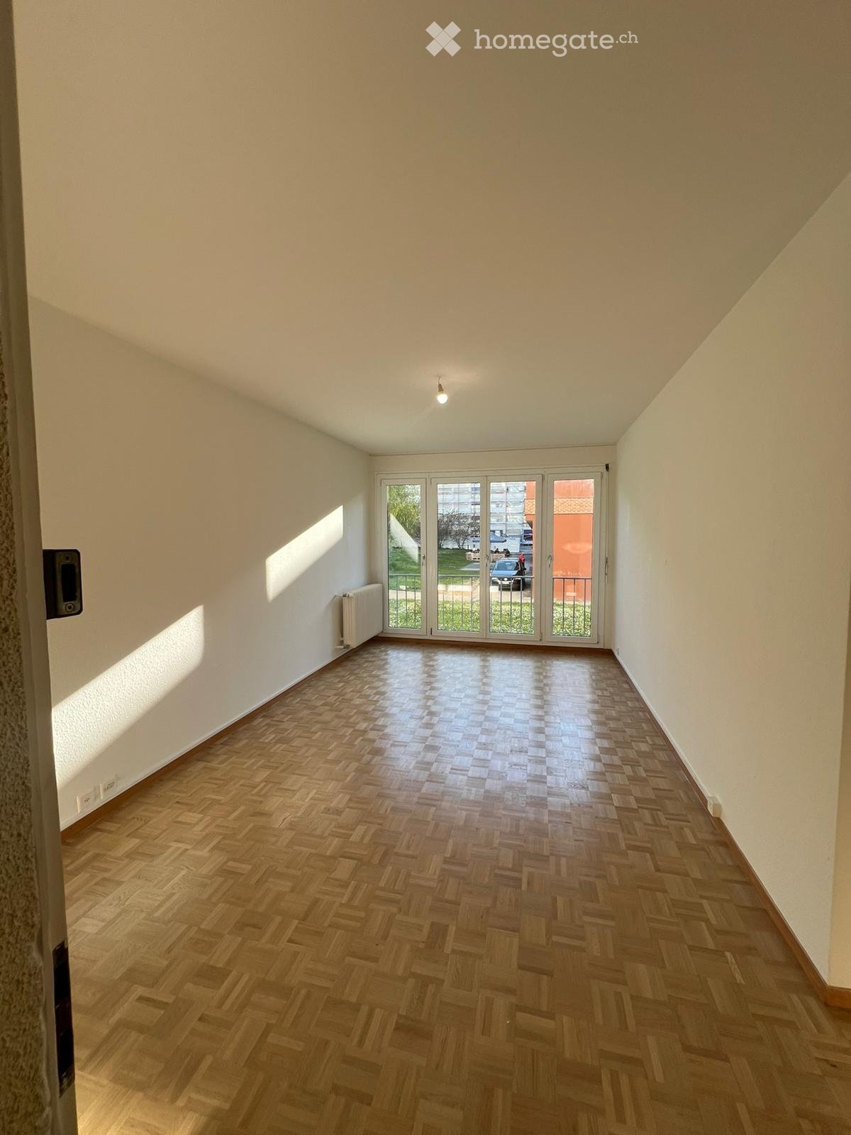 empty room, wooden floor, white walls, sliding glass doors, balcony, radiator
