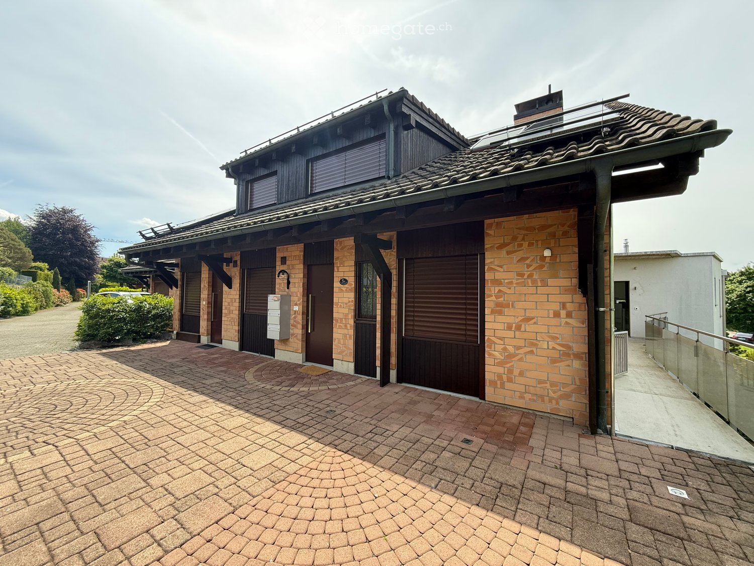 Two-story house with brick facade, garage, and curved brick driveway.