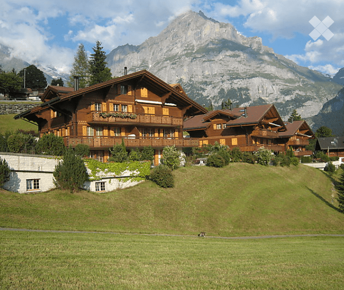 wooden chalet with large balconies, raised ground floor, surrounded by mountain range
