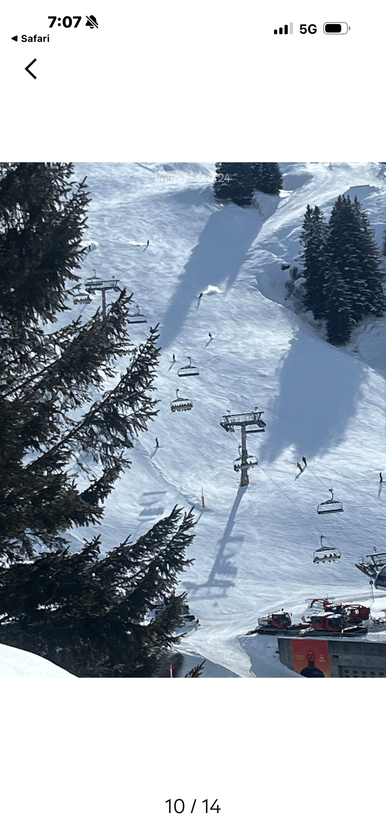 A snowy mountain slope with ski lifts and skiers, surrounded by evergreen trees.