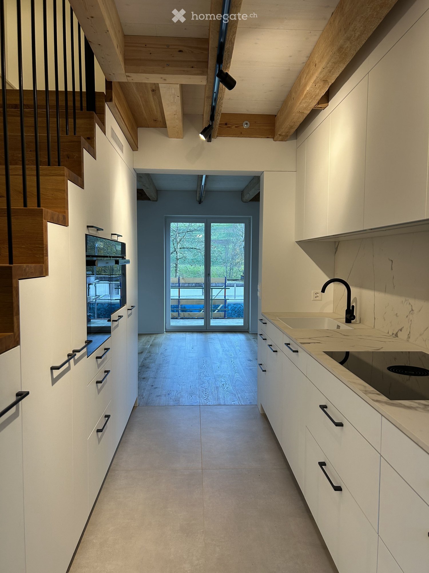 Modern kitchen with built-in oven, microwave, sink with faucet, wooden floors, large glass door