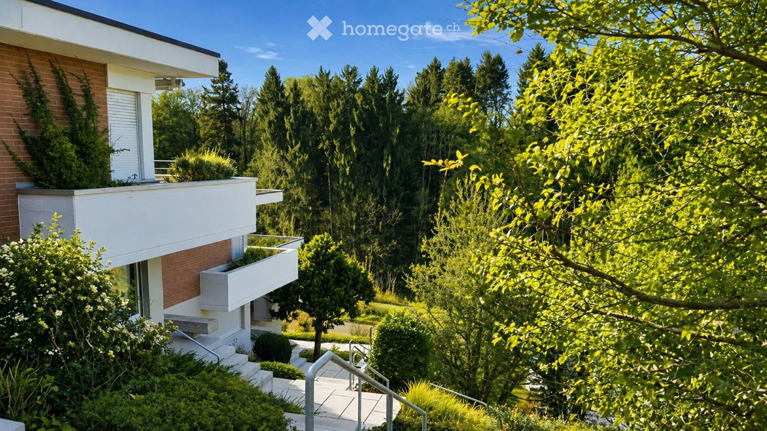 Modern building with brick and white exterior, surrounded by lush greenery and trees.