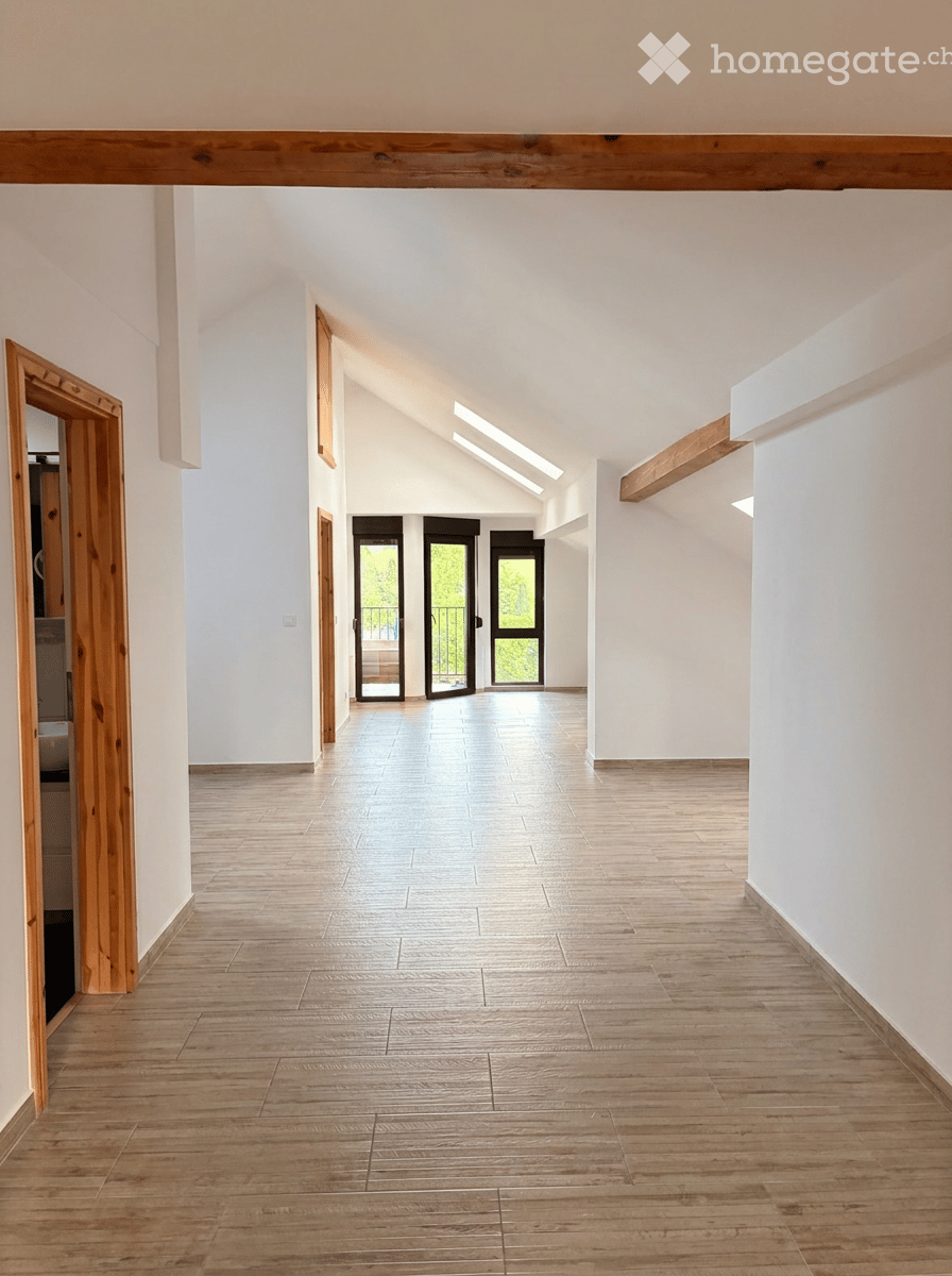 Bright, open hallway with wooden flooring, white walls, and large glass doors leading to an outdoor area.